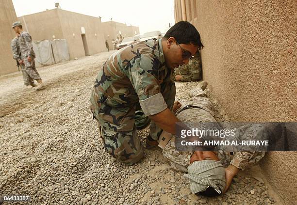 An Iraqi military rescue officer checks the pulse of a comrade during a training session on emergency rescue at the old Muthana airport in Baghdad on...