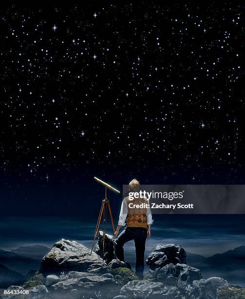 man gazing at a night sky aside a telescope  - telescope fotografías e imágenes de stock