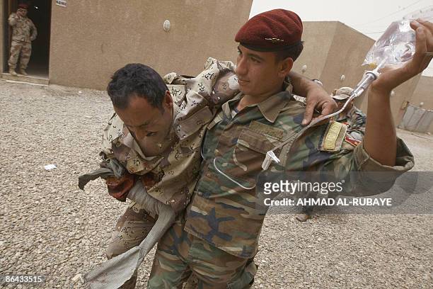 An Iraqi military rescue officer helps a comrade pretending to be injured during a training session on emergency rescue at the old Muthana airport in...