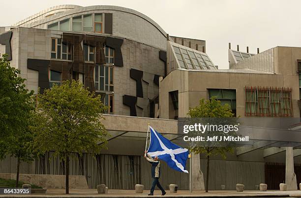 In this photo illustration, A man holds a Saltire flag outside the Scottish Parliament on May 6, 2009 in Edinburgh, Scotland. Today marks the 10th...