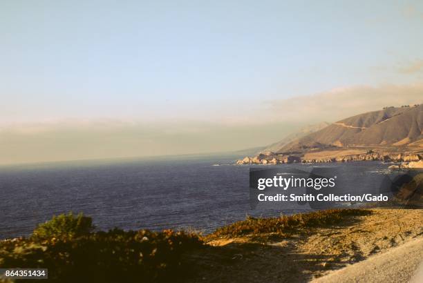 Cliffs and the Pacific Ocean near the site of Bixby Bridge, with California 1 highway visible in late afternoon sunlight, Big Sur, California, 1978.