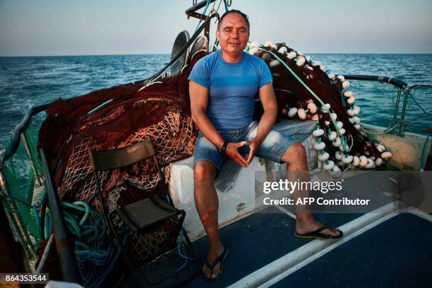 Stefan Toporau, the owner of a small local fishing company, poses next to one of his dolphin friendly fishing nets, aboard his boat on September 1,...