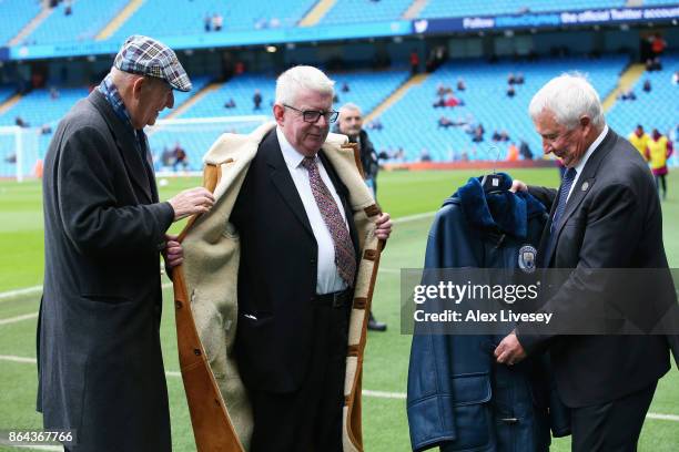 Commentator John Motson is presented with a coat by Manchester City life president Bernard Halford and former player Mike Summerbee prior to the...