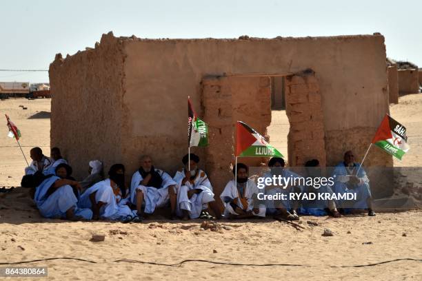 Sahrawi refugees sit in the shade at the Aousserd camp for Sahrawi refugees on the outskirts of Tindouf, south west of Algeria, on October 18, 2017.