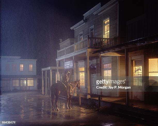 cowboy on horse in front of saloon in rain - saloon photos et images de collection