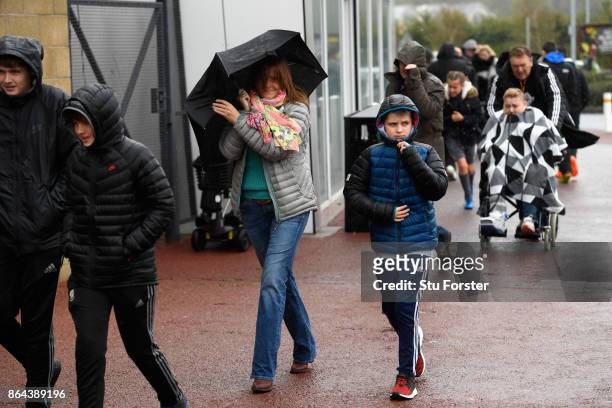 Fans attempt to keep dry prior to the Premier League match between Swansea City and Leicester City at Liberty Stadium on October 21, 2017 in Swansea,...
