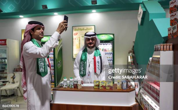 Picture taken on October 21, 2017 shows men draped in the Saudi and Iraqi flags standing by showcased food products at the Saudi Pavilion at the...