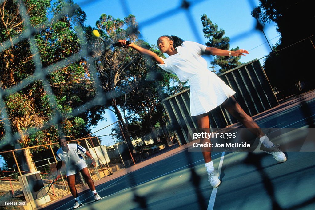 Tennis, doubles match, woman playing forehand return by net