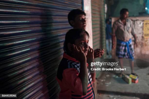 October 18: A boy holds his ears to block out the sounds as people in the Purasawakkam set off firecrackers and sparklers to celebrate Diwali night...