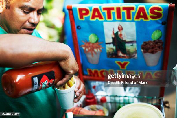 a street vendor pours hot sauce into a cup in the xochimilco district of mexico city - mexico city street vendors stock pictures, royalty-free photos & images