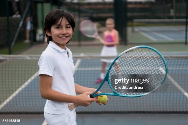 happy boy playing tennis outdoors with a friend - country club stock pictures, royalty-free photos & images