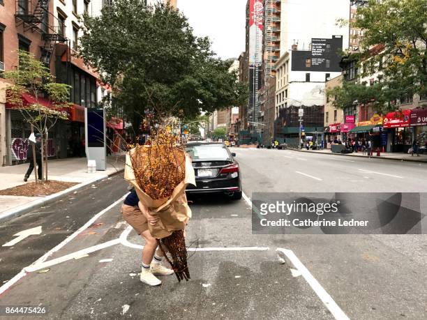 man picking up large dried plant wrapped in brown paper on the street - covered car street stock pictures, royalty-free photos & images