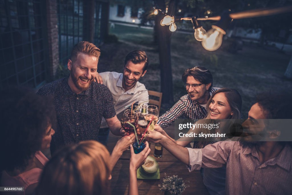 Grupo de amigos felizes torrar em uma noite de festa no quintal.