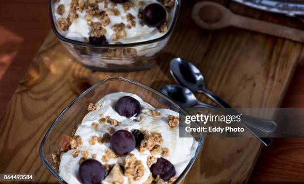 yogur, granola, miel y uvas listas para el desayuno dispuestas en bol de cristal - desayuno stock-fotos und bilder