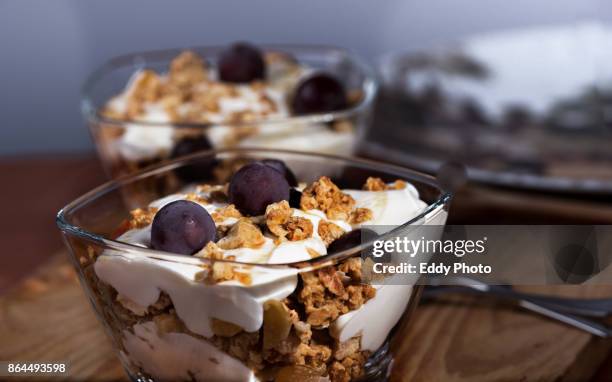 yogur, granola, miel y uvas listas para el desayuno dispuestas en bol de cristal - desayuno stock-fotos und bilder