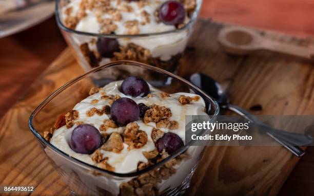 yogur, granola, miel y uvas listas para el desayuno dispuestas en bol de cristal - desayuno stock pictures, royalty-free photos & images