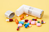 White asthma inhaler and colorful pills drug