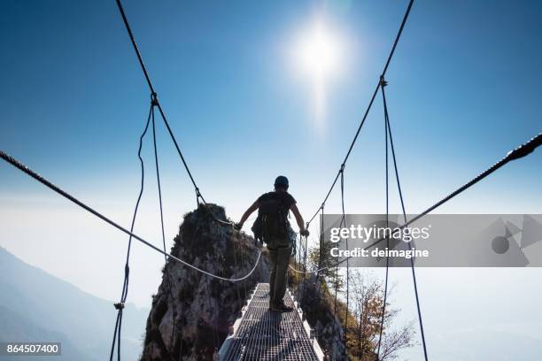 grimpeur de femme sur le dessus de la montagne au coucher du soleil - pont suspendu photos et images de collection