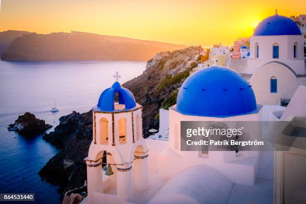 sunset over blue dome church tops and volcanic landscape in santorini - fira santorini stock pictures, royalty-free photos & images