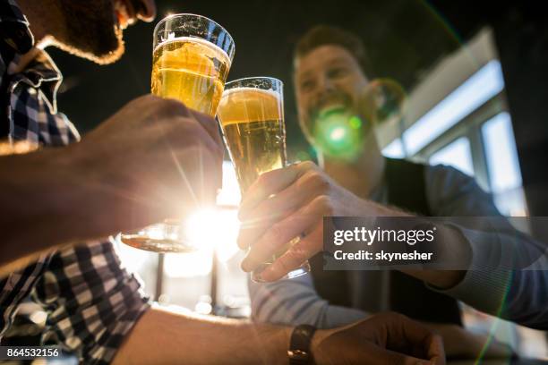 close up of male friends toasting with beer in a cafe. - pub mates stock pictures, royalty-free photos & images