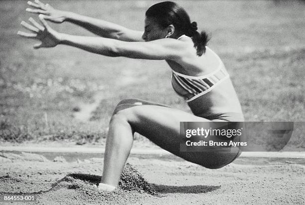 athletics, woman landing on sand at long jump event (b&w) - verspringen stockfoto's en -beelden