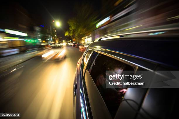woman in rear of car driving through new york city - driving a car at night stock pictures, royalty-free photos & images