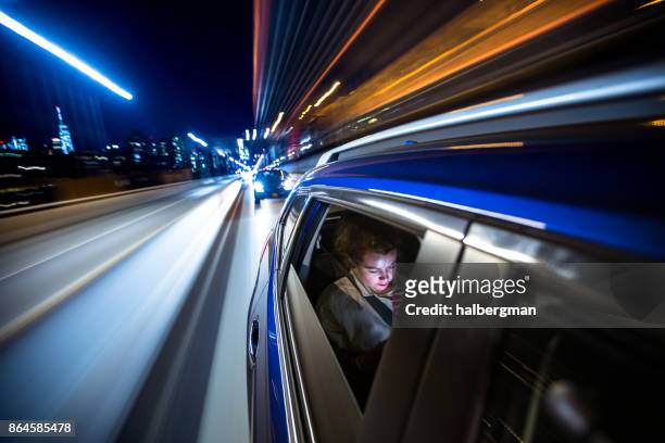 woman in rear of car driving through new york city - long exposure car stock pictures, royalty-free photos & images