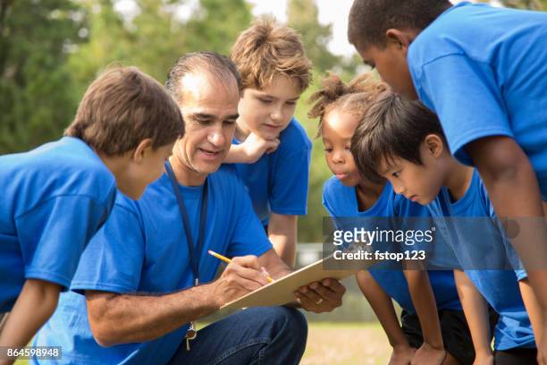 soccer team coach explains next play to his children's team. - coach stock pictures, royalty-free photos & images
