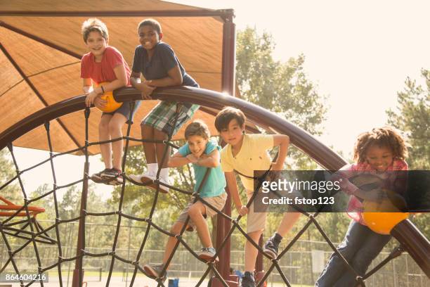 multi-ethnic group of school children playing on school playground. - jungle gym stock pictures, royalty-free photos & images