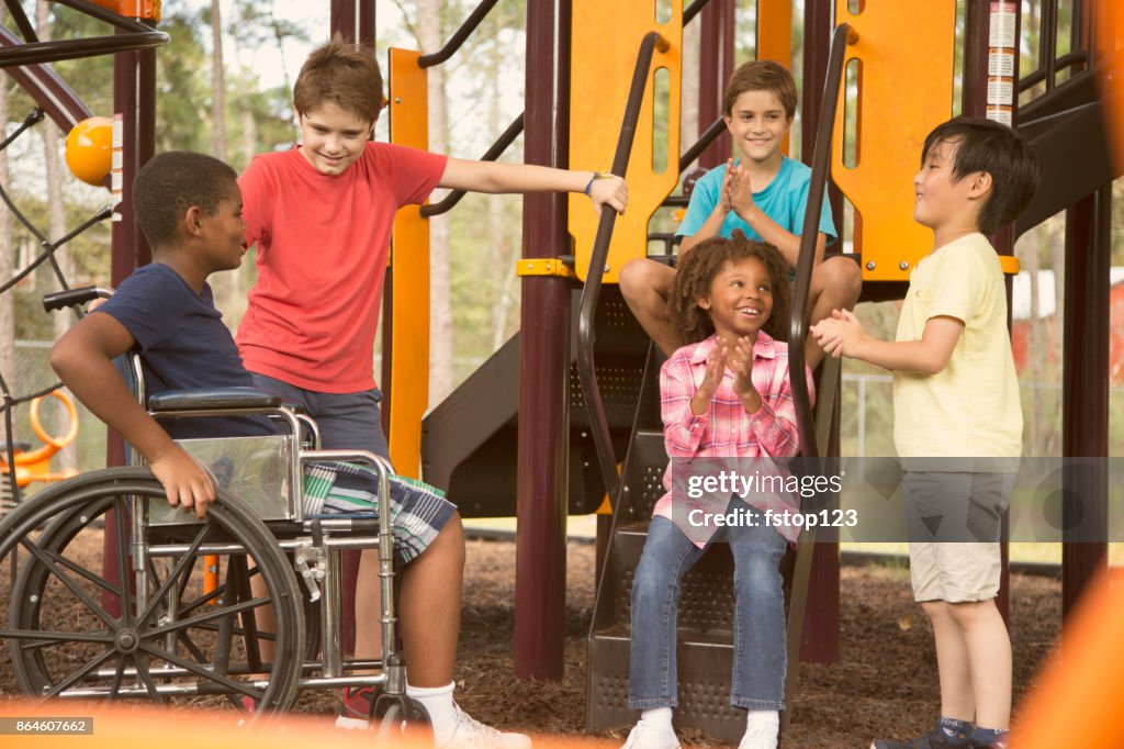 Multi-etnische groep van school kinderen op het schoolplein, een rolstoel.