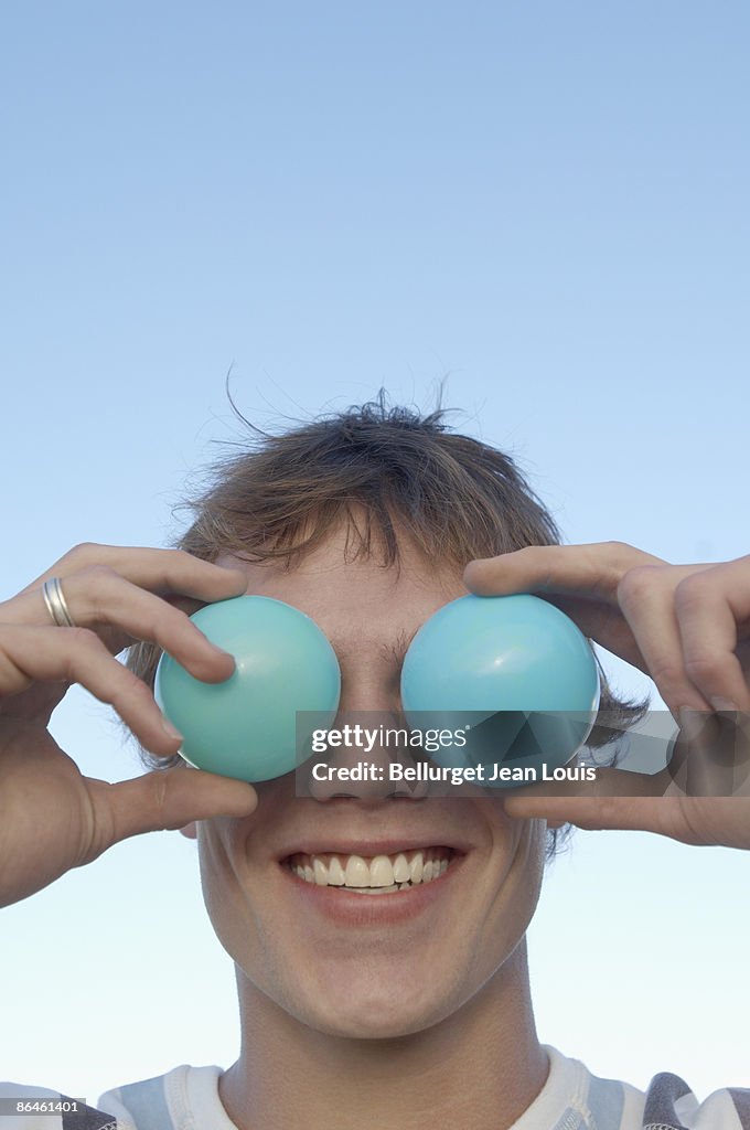 Man covering eyes with blue balls