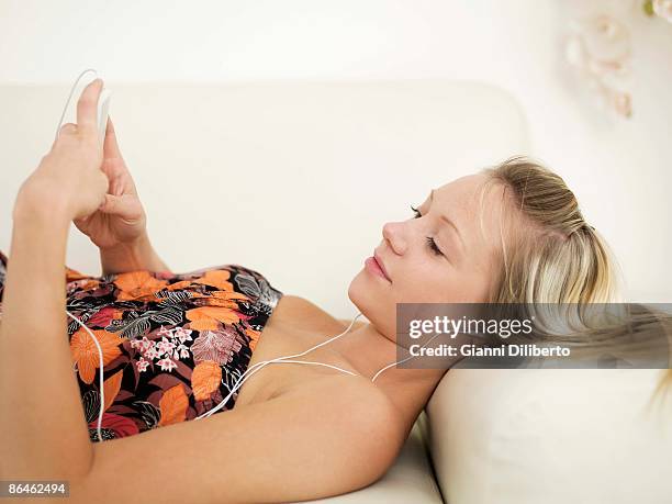 teenage girl reclining with mp3 player - lying on back girl on the sofa stock pictures, royalty-free photos & images