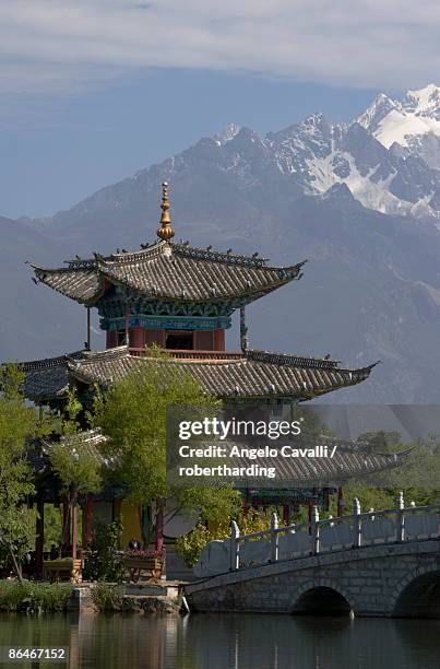 black dragon pool park, temple and bridge, with jade dragon snow mountain in background, lijiang, yunnan province, china, asia - black dragon pool park stockfoto's en -beelden