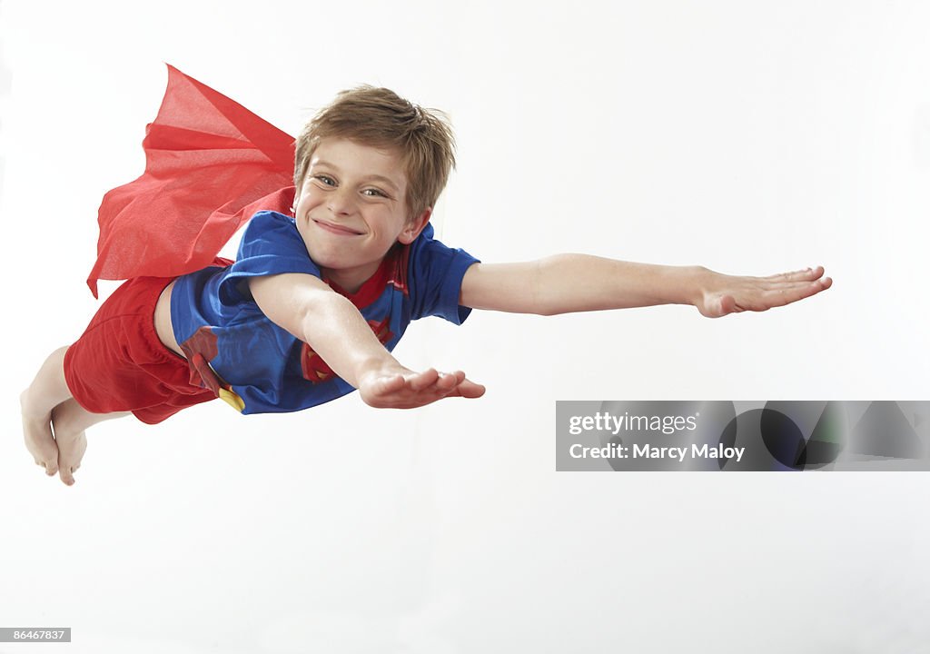 Boy on super hero costume flying through the air.