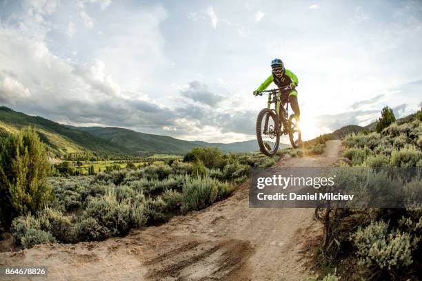 woman jumping with a mountain bike at sunset. - andare in mountain bike foto e immagini stock