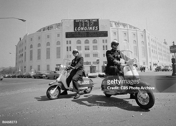 Exterior of Yankee Stadium with motorcycled police and cars parked outside, New York, April 1967.