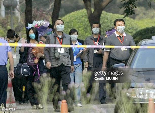 Chinese woman walks with health officers as she is released from a medical surveillance for influenza A at a sealed off hotel in Beijing on May 7...