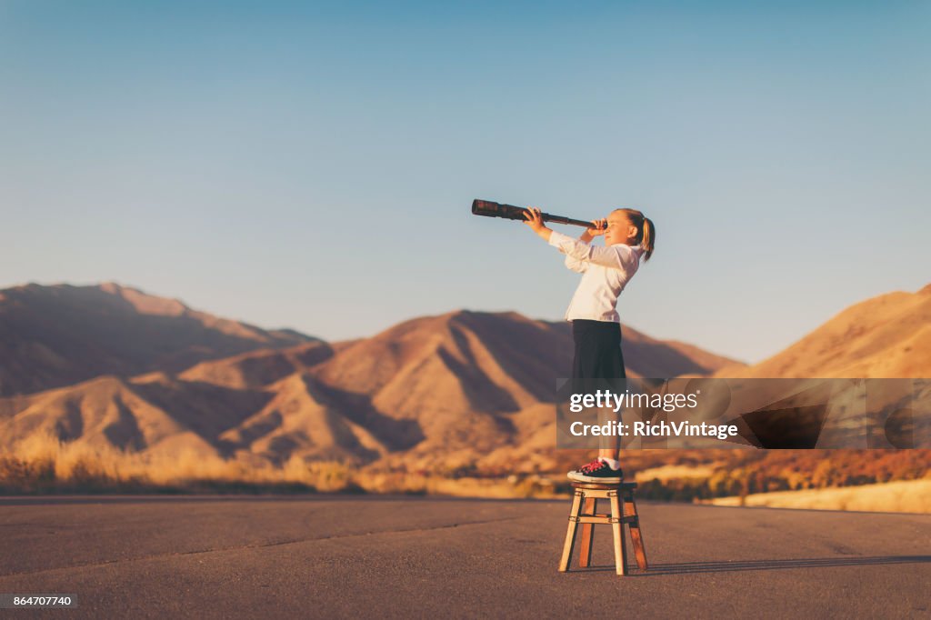 Chica joven se ve a través de telescopio