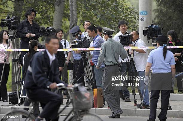 Masked security guard patrols a cordon in front of the gathered media in Beijing on May 7, 2009 near the entrance of a sealed off hotel before...