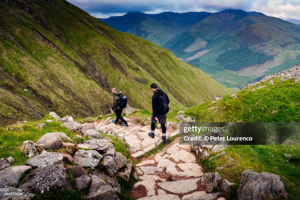 Two hikers walking down a path