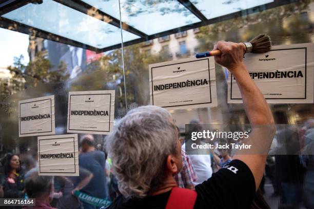 Man pastes posters on to a bus shelter as protesters gather in the city center to demonstrate against the Spanish federal government's move to...