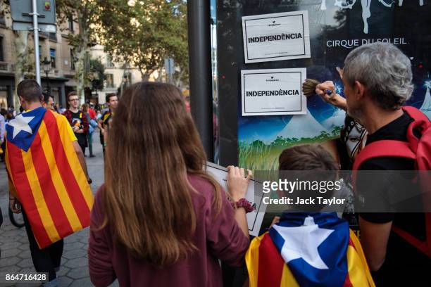 Man pastes posters on to a bus shelter as protesters gather in the city center to demonstrate against the Spanish federal government's move to...