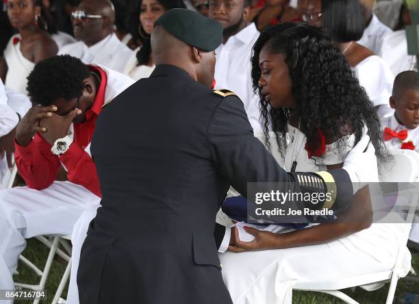 Myeshia Johnson is presented with a folded American flag by a military honor guard member during the burial service for her husband U.S. Army Sgt. La...