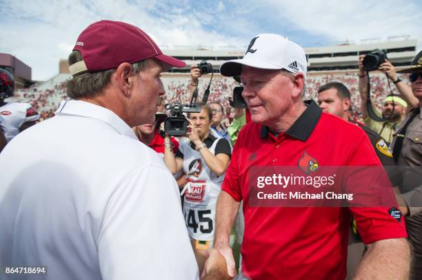 Head coach Jimbo Fisher of the Florida State Seminoles shakes hands with head coach Bobby Petrino of the Louisville Cardinals after their game at...