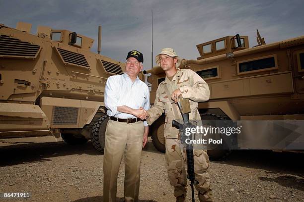 Secretary of Defense Robert Gates poses for a picture with a U.S. Navy serviceman in front of MRAP armoured personnel carriers following a meeting...