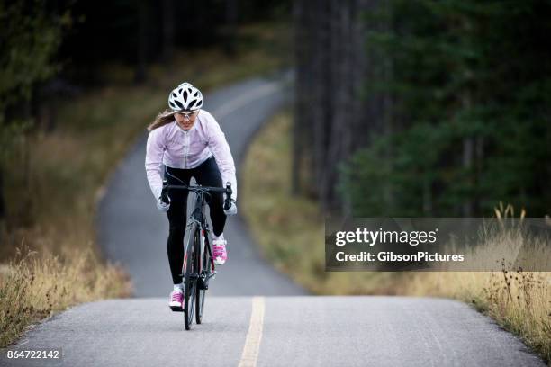 a woman rides her road bike along the trans canada trail bikepath near canmore, alberta, canada in the autumn. - bicicleta de corrida imagens e fotografias de stock