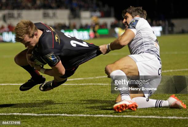 Nick Tompkins of Saracens scores a try despite the efforts of James Hook of Ospreys during the European Rugby Champions Cup match between Saracens...