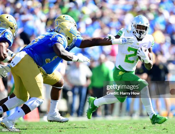 Royce Freeman of the Oregon Ducks fends off the pursuit of the UCLA Bruins defense as he runs during the first half at Rose Bowl on October 21, 2017...