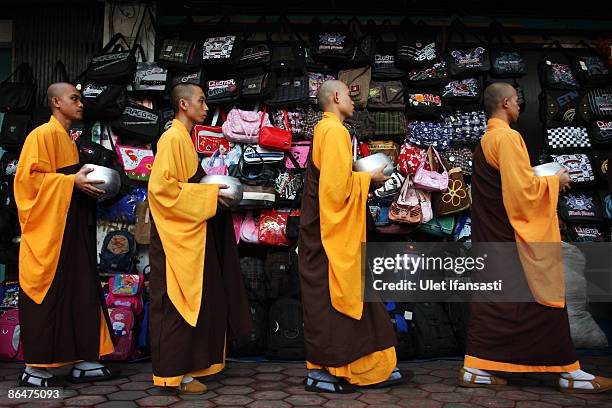 Buddhist monks prepare to receive religious meals from Buddhist members of the public as they walk around the streets on Vesak Day, commonly known as...