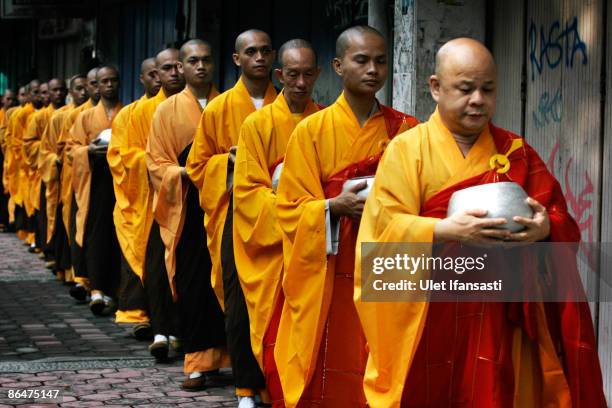 Buddhist monks prepare to receive religious meals from Buddhist members of the public as they walk around the streets on Vesak Day, commonly known as...